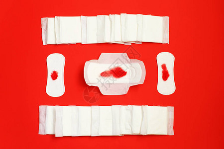 红色背景上的卫生巾和吸水床单月经垫和卫生棉条女人危急日子图片