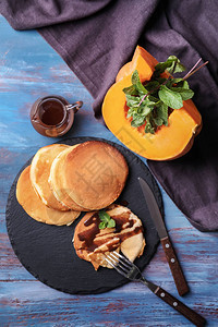 火热南瓜煎饼和彩色木制餐桌上巧克力酱汁加热南瓜图片
