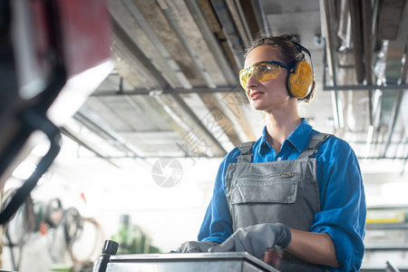 在金属车间或工厂勤奋操作机床的女工图片
