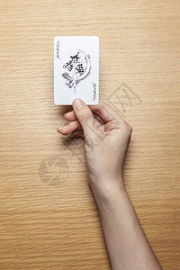女人手拿着一张卡片放在木桌上图片