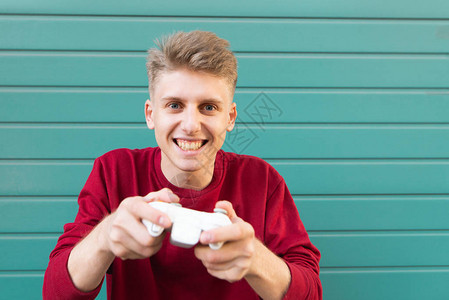 手里拿着游戏手柄的快乐游戏玩家在绿松石背景上玩游戏机图片