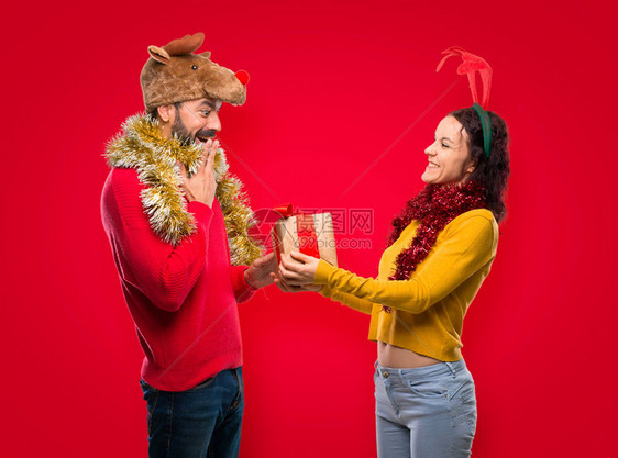 一对为圣诞节日打扮的夫妇带着孤立的红色的礼图片