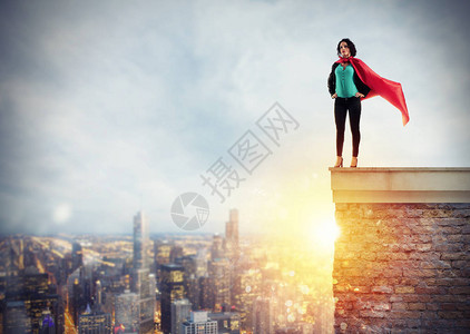 成功的女商人在日出时表现得像一个超级英雄在建筑物的屋顶上决心图片