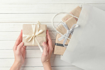 女人双手用礼物袋包着礼物在白色背景最图片
