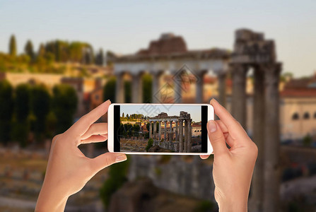一位游客正在为罗马论坛拍照晚上土星神庙的柱子罗马图片