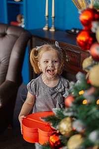 非常美丽的小女孩站在圣诞树上带着礼图片
