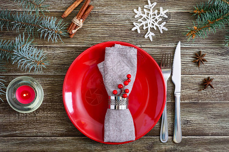 圣诞餐桌布置红盘子餐巾纸叉子刀子木桌上的树枝圣诞节图片