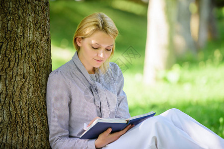 畅销书排行榜每个女孩都应该读的书放松休闲爱好概念最好的女自助书籍女孩集中坐在公园瘦树干上看书阅读鼓背景图片