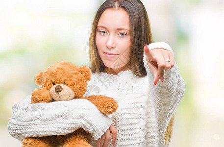 年轻的白种女人在孤立的背景下抱着泰迪熊图片