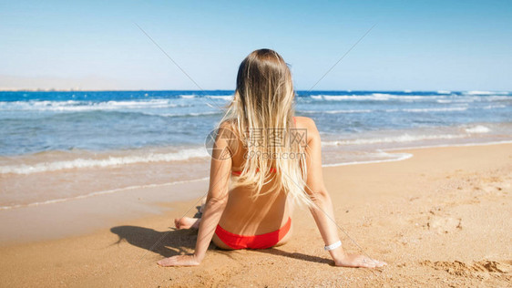 坐在沙滩上看着地平线的金发长头图片