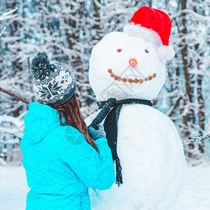 女人在寒冷的冬日概念中堆雪人图片