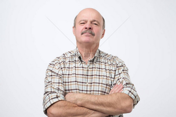 自私的老人在胸前交叉手的肖像图片