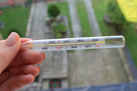 玻璃水银温度计在后院背景的手中测量水银温度计图片