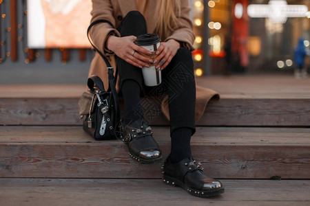 金发少女身着秋季保暖外套时尚黑色牛仔裤黑色皮革复古时尚现代鞋和时尚包图片