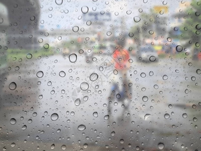 关闭玻璃背景上的雨滴道路上的交通失焦图片