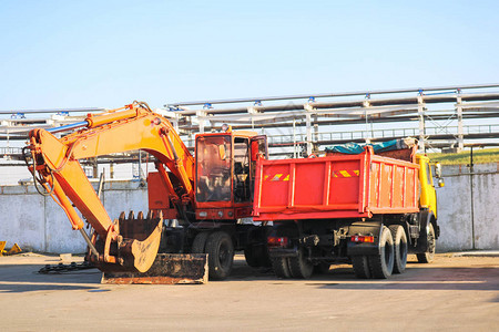 一辆带有拖车自卸车和带钢包的挖掘机的大型重黄橙色卡车在建筑图片