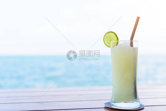 棕色木头桌上的一杯柠檬汁早上有海景和天空背景假期和休图片