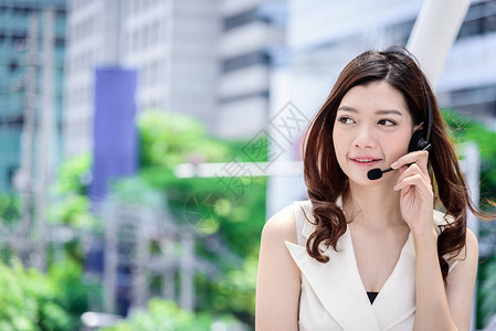 Asian商业妇女以建筑和城市背景在办公室外办公并经营业务图片