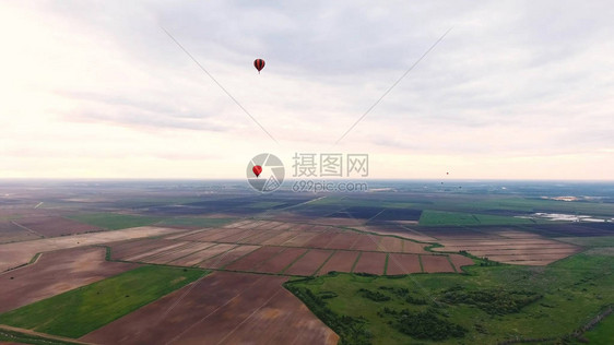 鸟瞰图热气球在美丽的天空和日落的乡村田野上空浮空图片