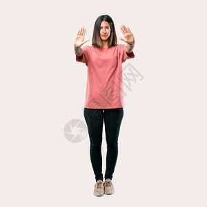 整具年轻女孩的全身穿粉红色衬衫用她的手停止手势否认一种认图片