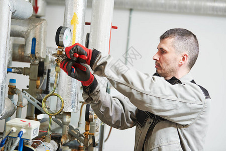 加热设备检查工程师或水管工在锅炉房拧紧或调节图片