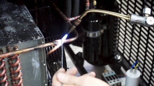 一名工人正在使用燃气烧器和焊料接铜管工人燃烧器加热细节一家工厂的金属工人使用轨道燃烧器图片
