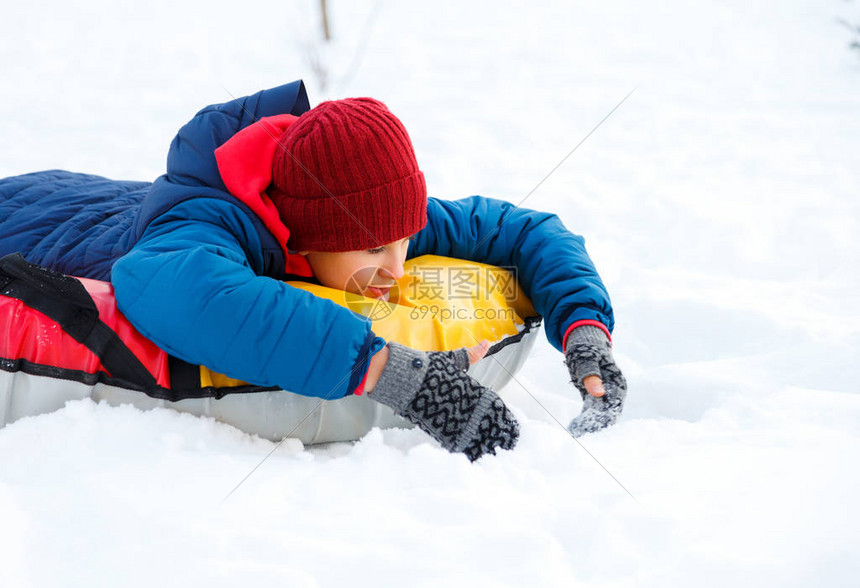 英俊的青少年在滑下山时笑着表现出兴奋在户外的冬日雪管快乐可爱兴奋的男孩在下雪天橇下图片