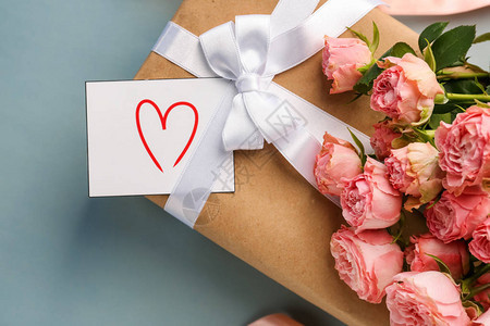 美丽的玫瑰和带有灰色背景卡片的礼物盒情图片