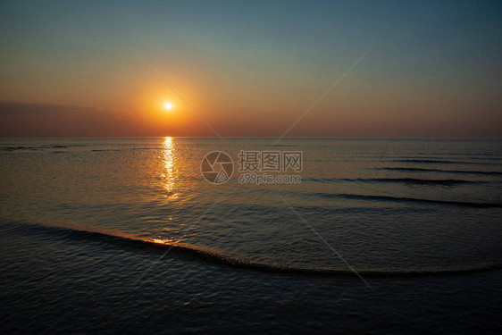 夏季在平静的海面上黄橙色日落阳光照耀图片