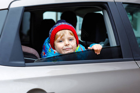 坐在汽车座椅上的漂亮蹒跚学步的男孩的画像儿童运输安全可爱的健康小男孩站在交通堵塞的情况下图片