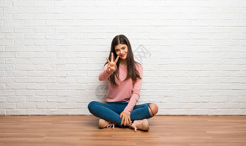 年轻女孩坐在地板上在一间快乐的房间里数图片