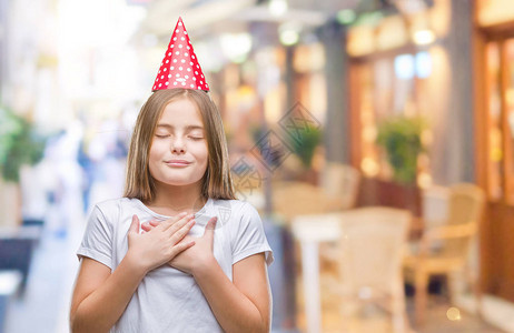 年轻漂亮的女孩在孤立的背景下戴着生日帽图片