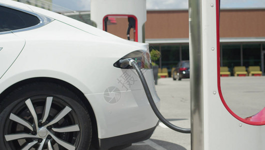 白色特斯拉自动电汽车在超级充电站充电图片