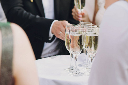 服务员在户外的婚礼招待会为客人提供盛装香槟杯的餐具背景图片
