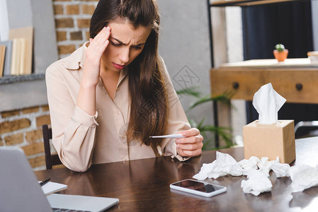 拥有温度计并检查办公室温度的年轻女企业家图片