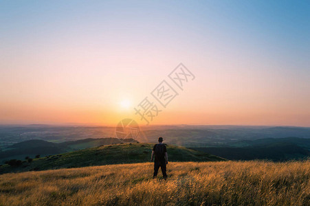 一个山丘上的徒步者看着整个英国风景朝日落的图片