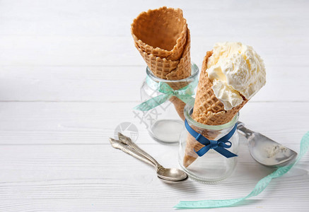 在白桌上的罐子里放着美味冰淇淋的华夫蛋筒背景图片