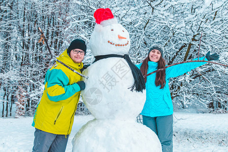 夫妇在冰冻的冬日概念中堆雪人图片