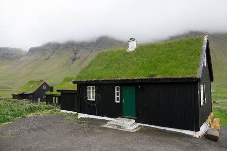 传统的小村庄位于法罗群岛陡峭山丘下风景秀丽的草地山谷图片