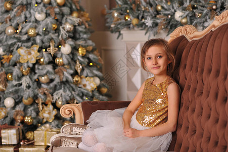 身着金色亮片女孩服装的女孩坐在新年树图片