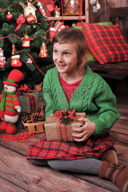 一个穿红绿衣服的女孩在圣诞树附近打开新图片