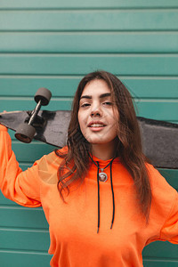 微笑的女孩是一个穿着街头服饰的街头溜冰者图片