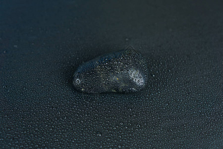 黑色背景上有水珠的黑色石头图片