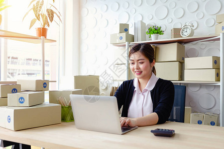 坐在办公室看电脑屏幕手持笔记本机微笑工作SME小企业的生活图片