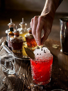 酒保在酒吧里用月桂叶制作红色鸡尾图片