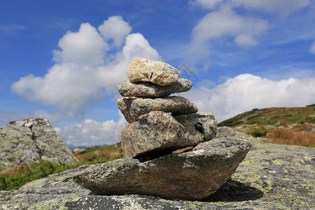 蓝天云下山中平衡的石头图片