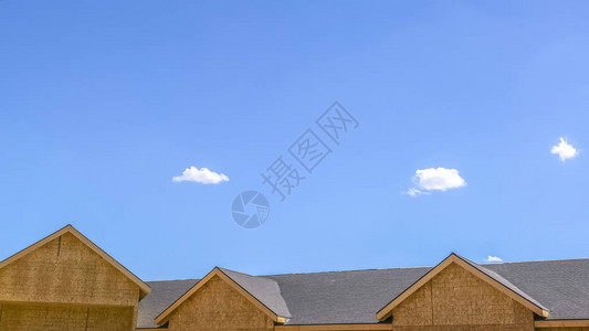 一个家的屋顶有天空和云彩背景在阳光明媚的日子里近距离观察家的屋顶背景中可以看到广阔的蓝天和稀图片
