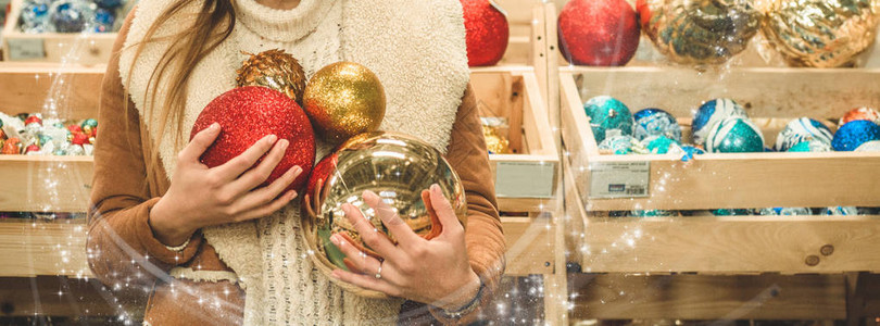 穿着温暖大衣的女孩拿着大球在圣诞节展会的购物中心为圣诞树盛宴举办图片