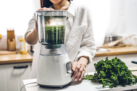 健康女喜欢在家中厨房做绿色蔬菜除毒净化和绿色水果冰淇淋及搅拌机的果汁背景图片