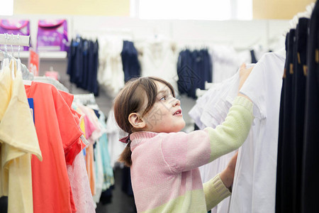 7岁女孩在儿童服装店中选择校图片